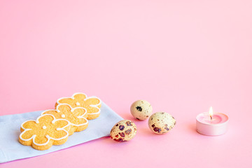 Selective focus to the still life made of corn biscuits, quail eggs and candle on a pink background. Copy space. Festive concept. 