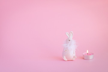 Bunny and candle on the pink background with copy space. Minimalistic Holidays concept. 