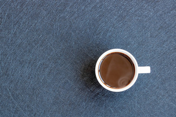 Black hot coffee in white cup on the dark background. Top view. Copy space.