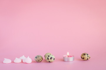 Festive still life made of quail eggs, candle and meringue on the pink background. Copy space. Holidays concept.  