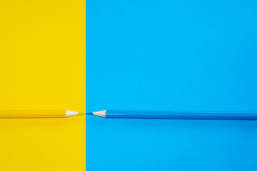 Yellow and blue pencil facing each other on vivid background. Minimal Aesthetic.