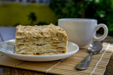 Cup of tea with cake on brown table background