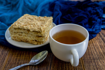 Cup of tea with cake on brown table background