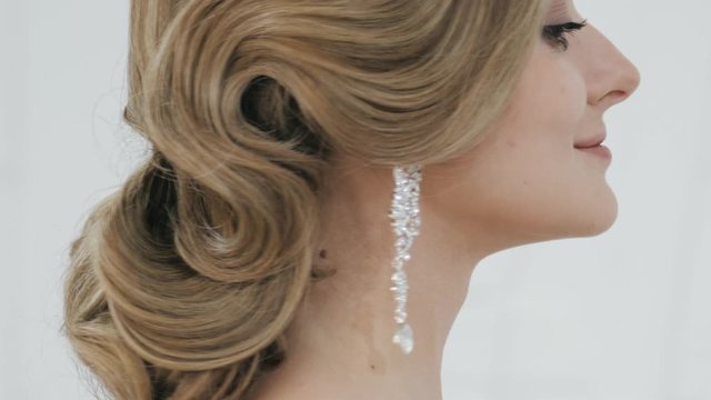Big close up shot of young blonde bride with gorgeous wedding hairstyle in tiara earrings turning head showing gorgeous wedding makeup and hairdo teasing and seductively looking in camera