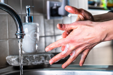 Proper washing of hands demonstrated at steel kitchen sink
