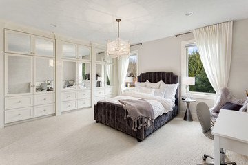 Bedroom in new luxury home with chandelier, desk, and abundant natural light