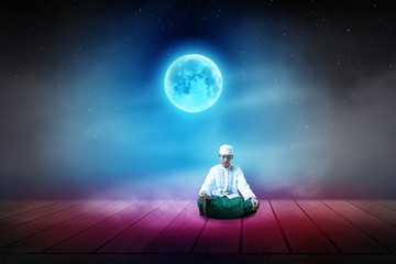 Fototapeta na wymiar Young man Asian moslem pray on the wooden floor with night sky full moon background 
