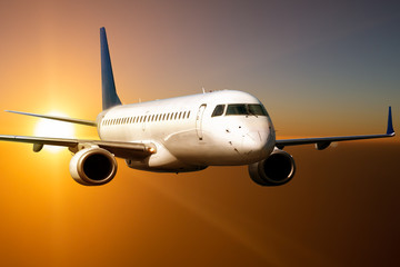 Fototapeta na wymiar White passenger jet plane flies above the clouds in the sunset light