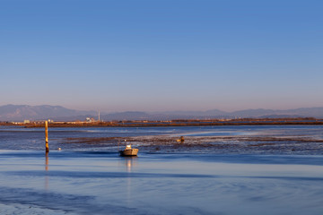 laguna di Marano Lagunare con barca di pescatore al tramonto.