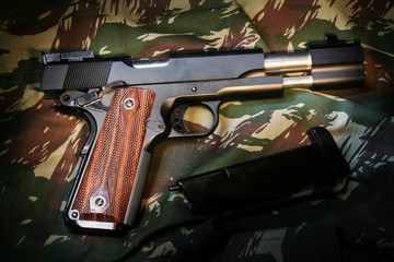 Pistola de airsoft com ferrolho deslizado em fundo camuflado © Rafael