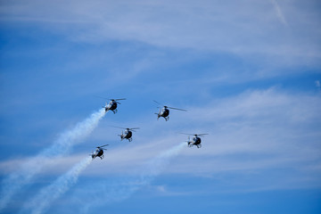 formation of five helicopters over sky with clouds