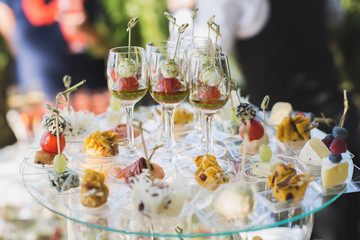 Reception at the wedding. Snacks and wine glasses on a glass table.