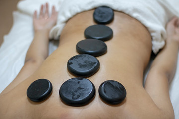 Massage with hot basalt stones. Beautiful girl relaxing in thai salon