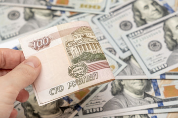 A hand holding one hundred ruble and american dollar banknotes on background, ruble devaluation and usd-rub exchange rate concept