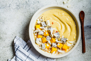 Mango smoothie bowl with granola and dragon fruit in white bowl, top view. Healthy breakfast concept.