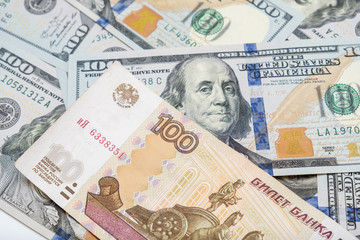 One hundred rubles lying on american dollars as a symbol of weakness russian national currency and strengthening of american dollar