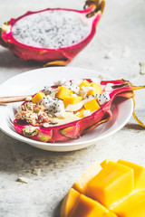 Dragon fruit filled with smoothie, mango and granola. Healthy vegan breakfast concept.