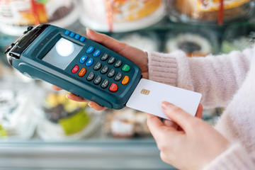 A woman inserts a Bank card into the payment machine. Hands close up. Top view. NFC concept,...