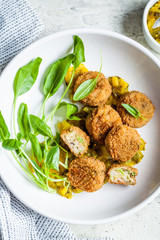 Vegan vegetable meatballs with spinach and green dressing, top view.