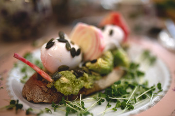 Healthy breakfast - poached eggs on bread with avocado and radish.