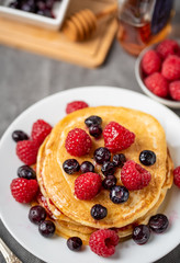 Sweet homemade pancakes with raspberries and blueberries on white plate.