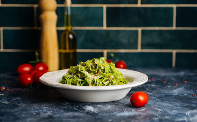 Italian pasta food background. Vegan italian pasta with spinach (Spinach Fettuccine Alfredo Pasta) on a white plate. Old kitchen background. Copy space