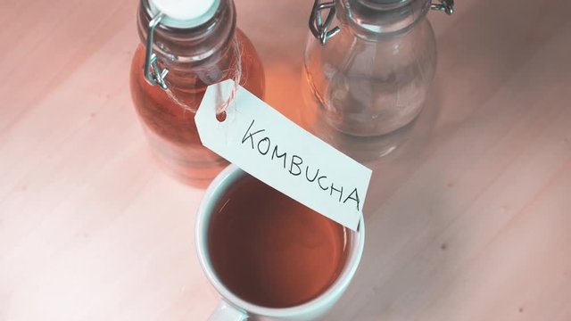 Handwritten label on a bottle of homemade Kombucha. It is a fermented drink made from tea and lemon, produced using culture SCOBY. Teal and orange style