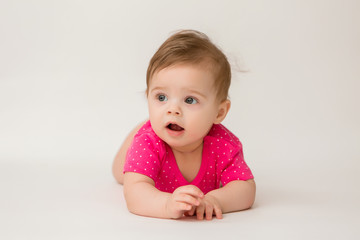 Fototapeta premium healthy baby girl in a pink bodysuit sits on a white background. space for text