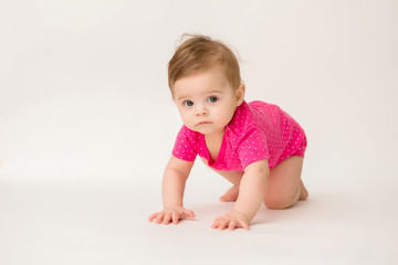 healthy baby girl in a pink bodysuit sits on a white background. space for text