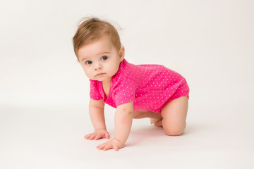 healthy baby girl in a pink bodysuit sits on a white background. space for text