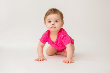 healthy baby girl in a pink bodysuit sits on a white background. space for text