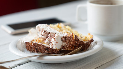 Tiramisu dessert in a plate, smartphone and a cup of coffee