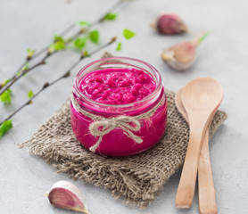 Horseradish with beetroot in a jar on a light background in rustic style