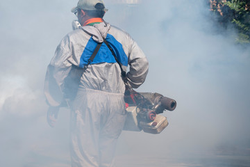 Softly focus of healthcare worker using fogging machine spraying chemical to eliminate mosquitoes...