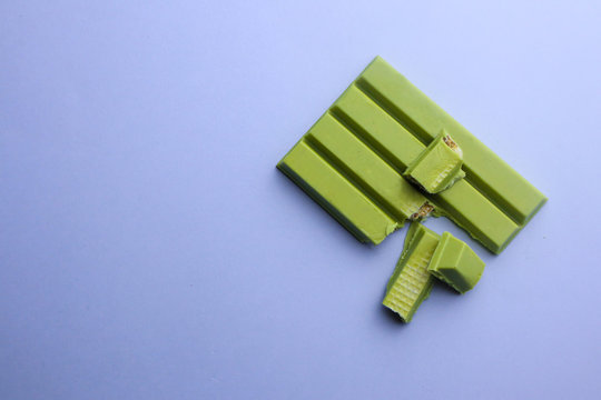 Tasty green chocolate on color background