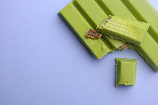 Tasty green chocolate on color background