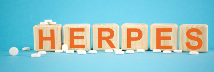 Herpes - word made on wooden cubes on light blue backround with tablets (pills) around. Healthy...