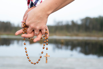 Couple pray together. Hands holding rosary symbol of love to God. Catholic religion cross. Walking...