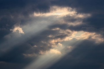 Light rays in sky under dark clouds.