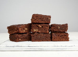 stack of square baked slices of brownie chocolate cake with walnuts