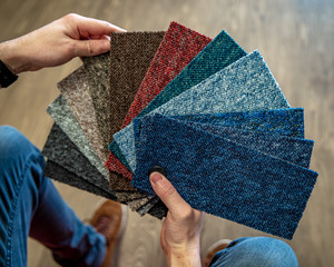 the man chooses the color of the new carpet according to the pattern book in the flooring shop
