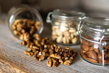 Walnut scattered on the white vintage table from a jar. Walnut is a healthy vegetarian protein nutritious food. Walnut kernels and whole walnuts on rustic old wood.