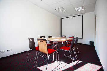 Interior of empty modern meetingroom. Conference room in a hotel for business training. Rows of chairs and desks. Boardroom with presentation screen and projector...