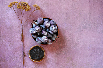 Frozen plum with ice cubes in a basket and a gravy boat with prunes, next to a field dried flower . Top view, copy space..