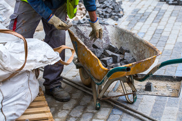 Construction work on pavement. Installation of concrete paver blocks on the sidewalk. The worker sorts the stone pavement.