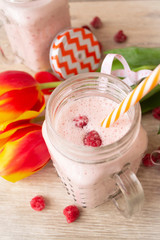 Beautiful appetizer pink raspberries fruit smoothie or milk shake in glass jar with fresh berries and tulips, top view. Yogurt cocktail. Close up. Natural detox. Liquid ice cream.