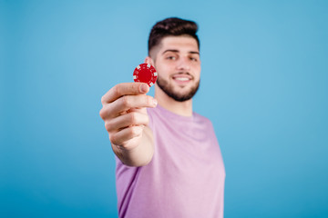 young handsome man with red poker chip on blue background