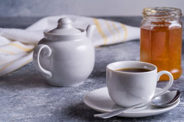 Cup of tea, teapot and jam on a table, blurred bokeh background.