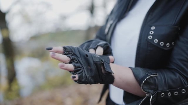 Female biker corrects her leather gloves. Close view