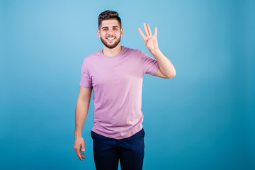 smiling man showing four fingers isolated on blue background